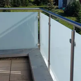 Balkongeländer aus Edelstahl mit satinierten Glasplatten und moderner Optik im Außenbereich.