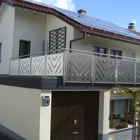 Modernes Einfamilienhaus mit Solaranlage und Balkon mit Edelstahlgeländer.