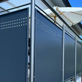 Moderner Sichtschutz aus Aluminium am Balkon mit Edelstahlgeländer und Sonnenschirm.