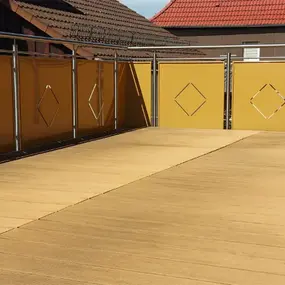 Große Terrasse mit gelbem Sichtschutz und Edelstahlgeländer, ideal für Balkonbau.