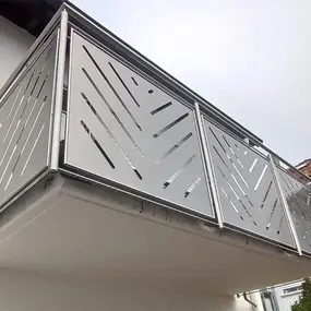 Moderner Balkon mit Edelstahlgeländer und geometrischen Designelementen am Haus.