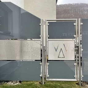 Moderner Sichtschutzzaun aus Glas und Edelstahl mit geometrischen Designelementen im Garten.