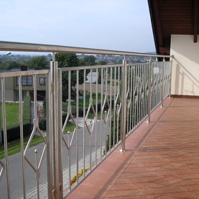Moderner Balkon mit Edelstahlgeländer und braun gefliestem Boden, Ausblick ins Wohngebiet.